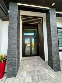 Elegant Entrance with Stone Pillars and Modern Design
        A modern entrance featuring textured stone pillars, sleek black glass doors, and layered wooden slats with integrated LED lighting, perfect for upscale architectural aesthetics.