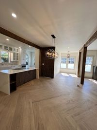 Bright and Open Kitchen with Natural Wood Flooring
        A stylish kitchen and dining area with natural wood flooring, exposed wooden beams, and modern lighting, offering a warm and inviting atmosphere for gatherings.