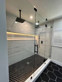 Luxury Modern Shower with Black Hexagon Tile: A sleek and modern glass-enclosed shower featuring large rain showerheads, a black hexagon tile floor, and elegant marble-effect wall tiles, creating a spa-like experience.