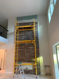 Close-up of scaffolding surrounding a white stone fireplace during installation, highlighting precision craftsmanship.