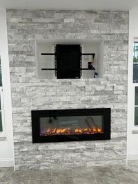 Elegant Stone Fireplace with Built-In TV Nook: A stylish gray stone fireplace with an electric insert and built-in TV mount, adding warmth and functionality to a modern living room design.