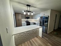 Luxurious kitchen adorned with premium black and white marble countertops, full backsplash, and a panoramic water view framed by a large picture window.