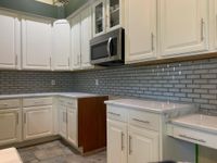 Sleek modern kitchen featuring a textured quartz island, stainless steel appliances, and warm wood finishes, combining elegance and functionality.